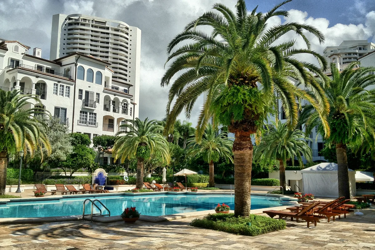 The Mediterranean Village at Williams Island with the 3000 Island Boulevard tower behind a palm-lined pool